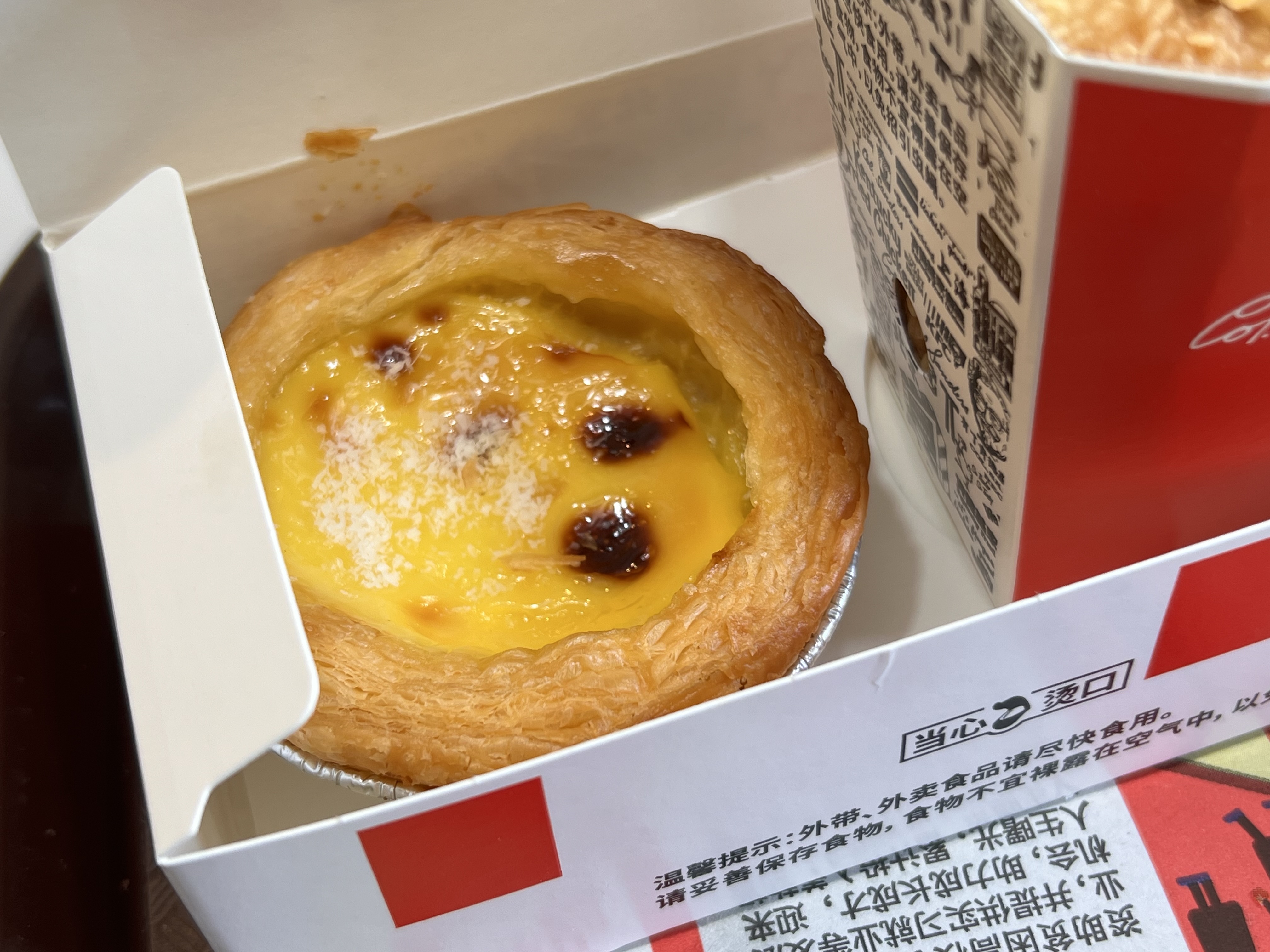 A photo of an egg tart in KFC packaging.