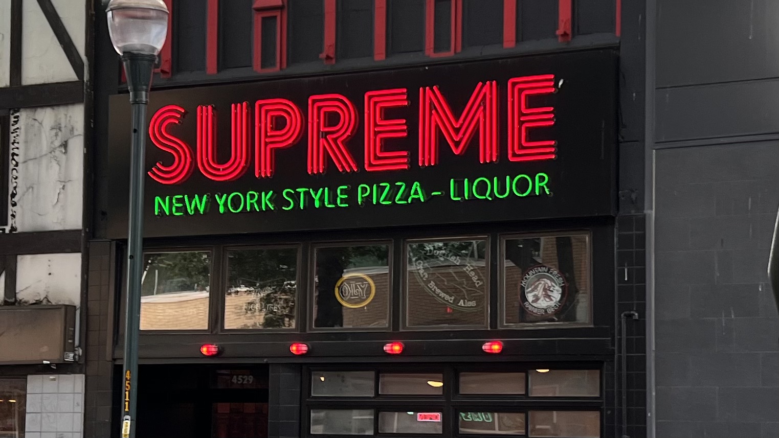 A photo of a restaurant storefront reading Supreme: New York Style Pizza-Liquor, but the dash between pizza and liquor could be mistaken for a hyphen